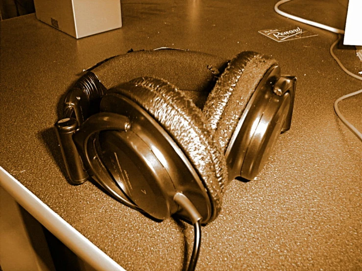 a silver headphone on a table, with cable connected