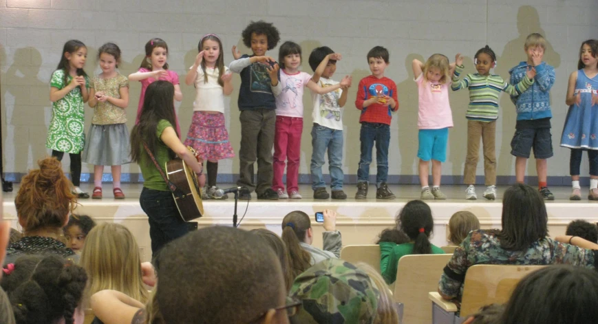 a group of children holding hands together on stage