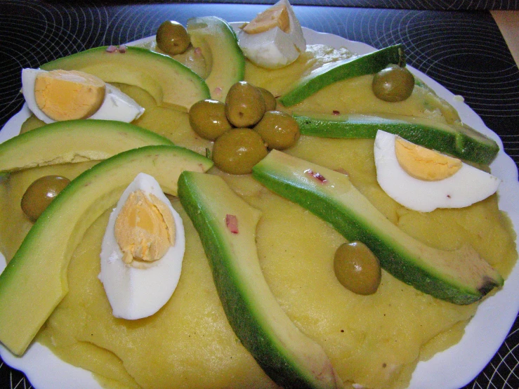 a white plate topped with cucumber and olives