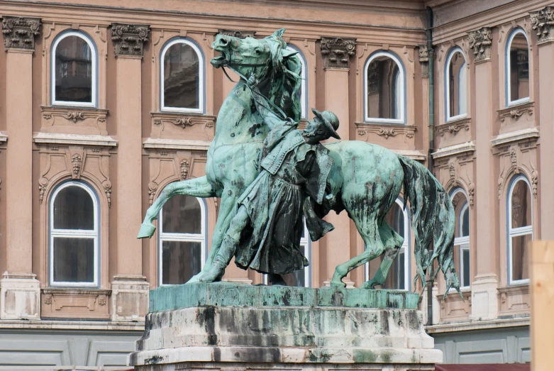 statue of two men riding on horses near a building