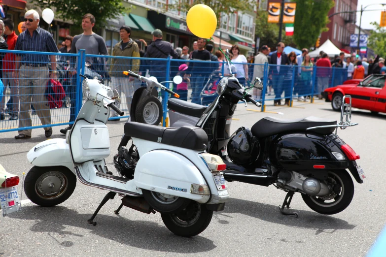 two mopeds parked on the street next to blue fence