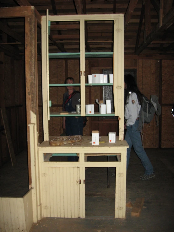 two people standing around a work area with a wooden cabinet