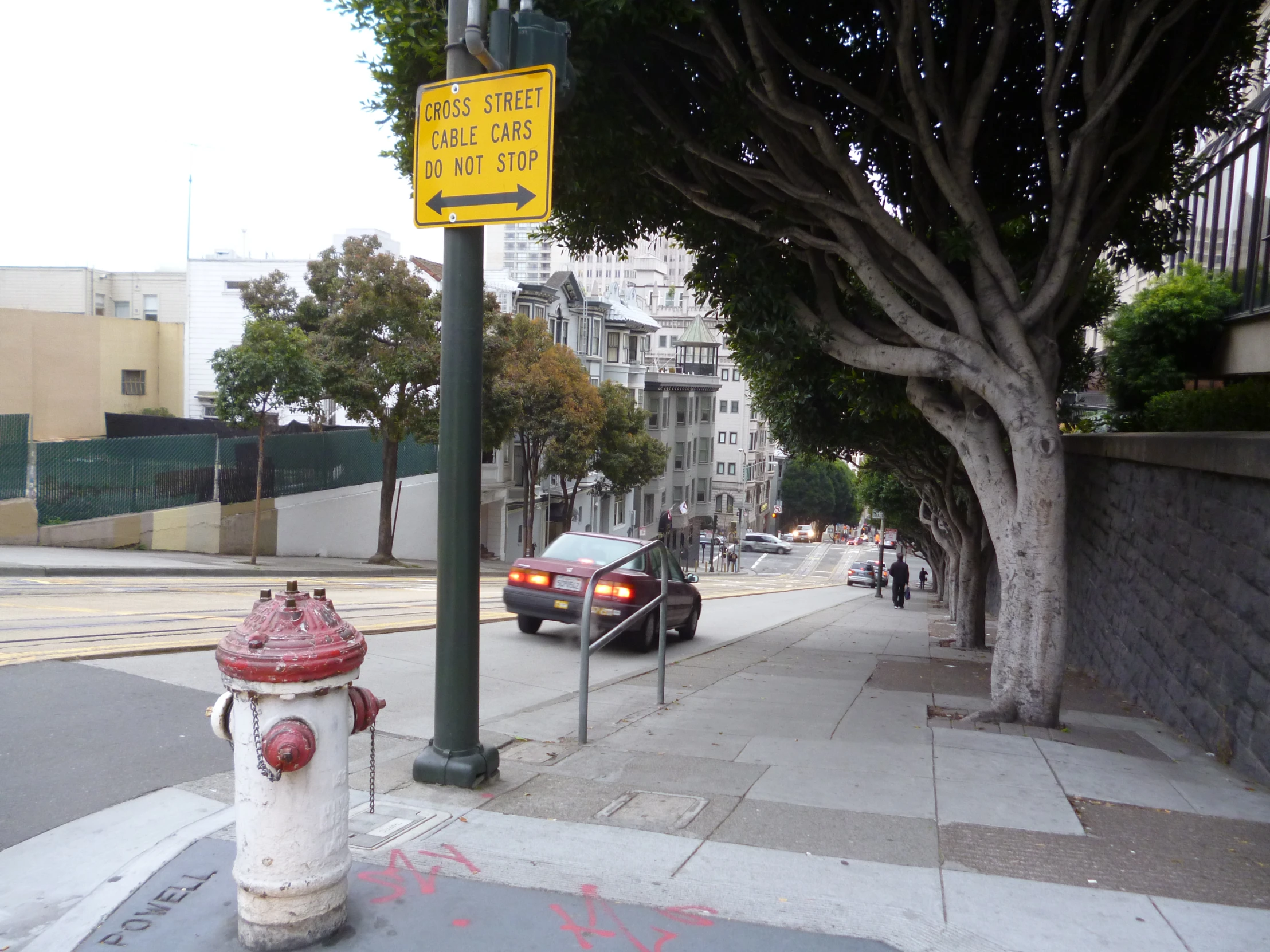 a fire hydrant is sitting on the sidewalk in front of a traffic sign