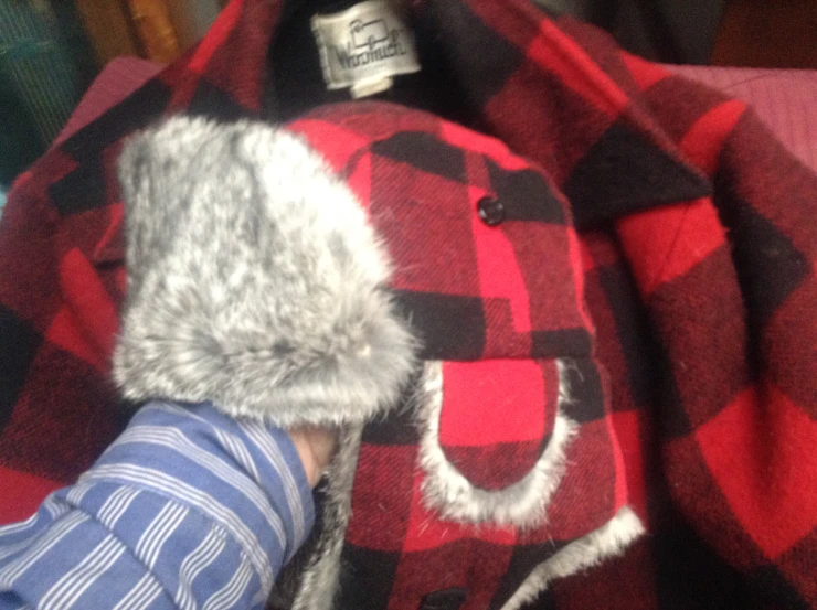 a person is holding a red and black plaid hat