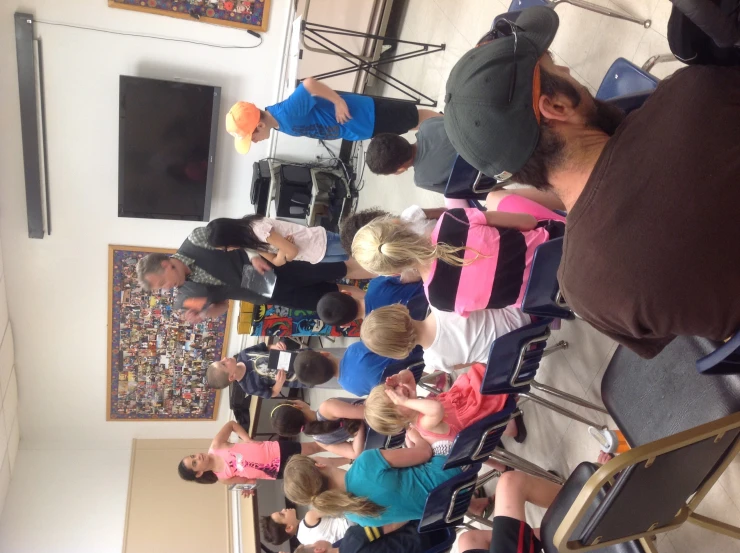 a group of children listening to two people in a class