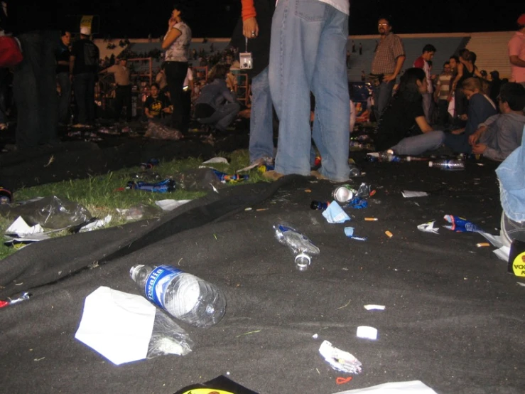 people are standing in the dark with scattered items and beer bottles