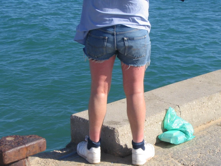 a person stands on the water edge with their shoes on