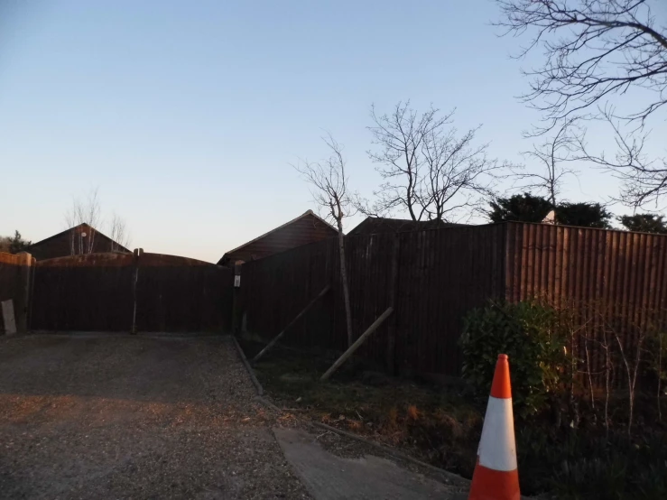 a fence, with a white and orange cone in the foreground