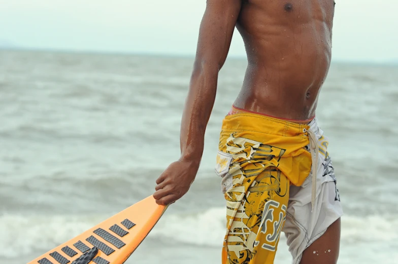 a man standing on a beach with his surfboard