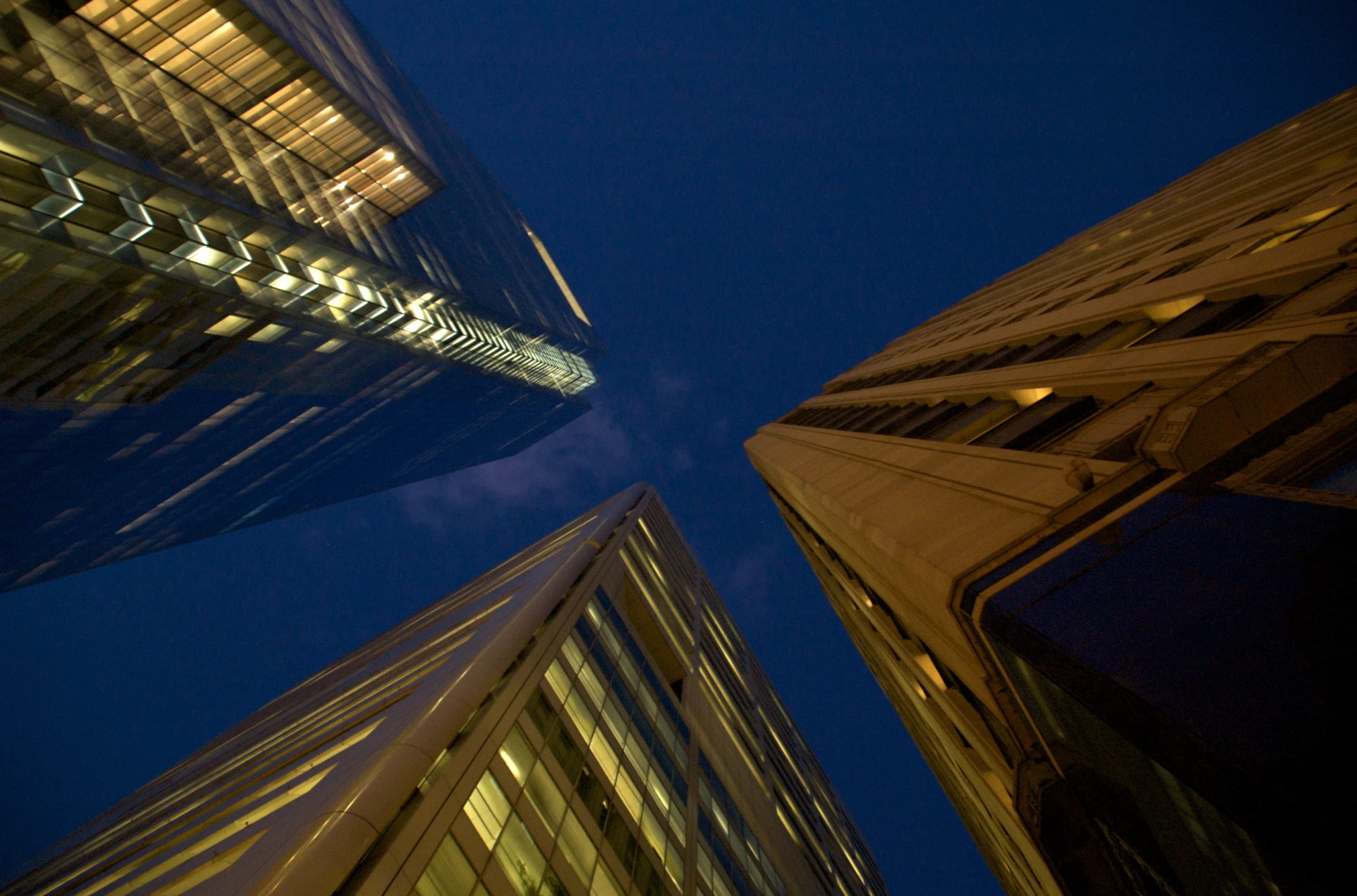 a view looking up at two tall buildings from another area at night