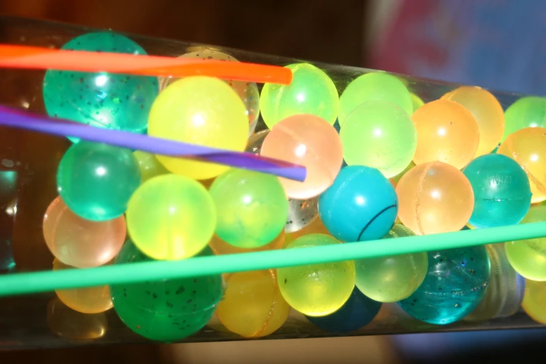 colorful plastic eggs and sticks in a tall glass