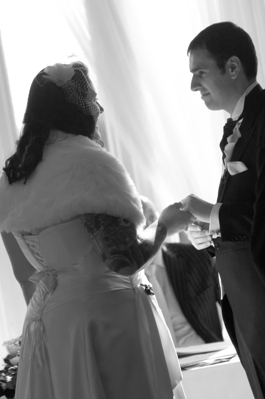 a young man is standing next to a woman in a wedding dress