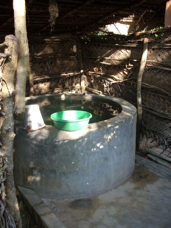 a green bowl is set in a concrete water trough