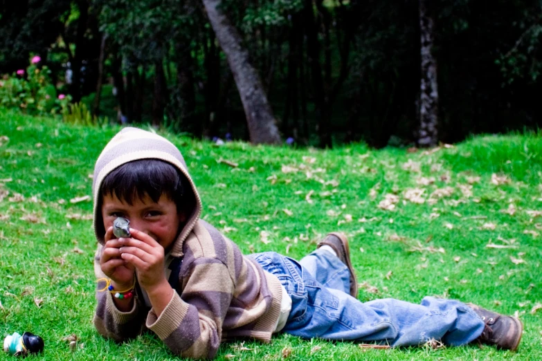 a child in a hood is laying on the grass