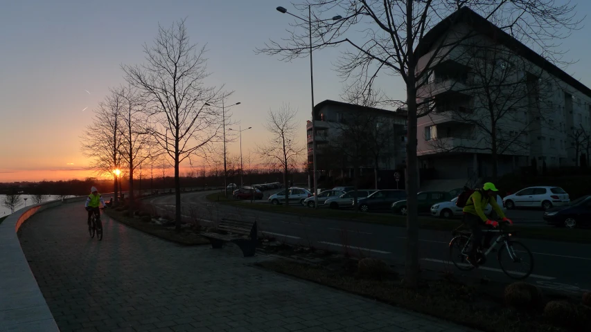 people riding their bikes along the side of a road at sunset