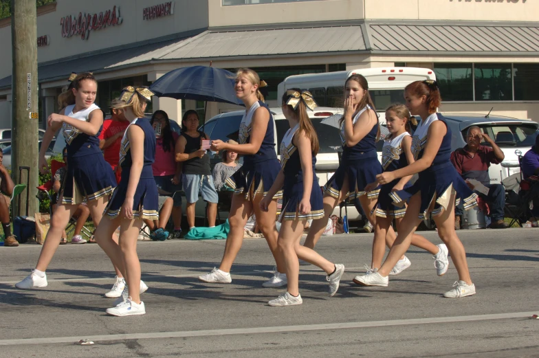 the girls walk in a parade holding umbrellas