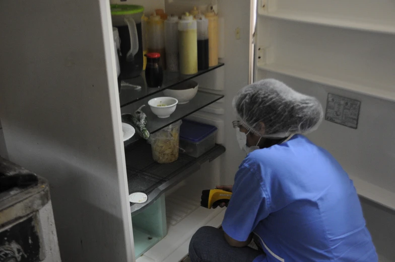 a woman sits in front of a pantry filled with food