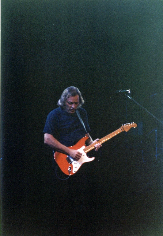 a man with a long hair playing guitar on stage