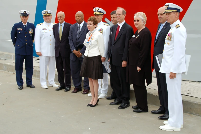 an group of people wearing suits standing next to a big ship