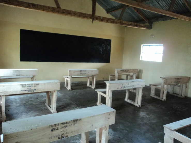 a room full of wooden benches with chalk writing on them