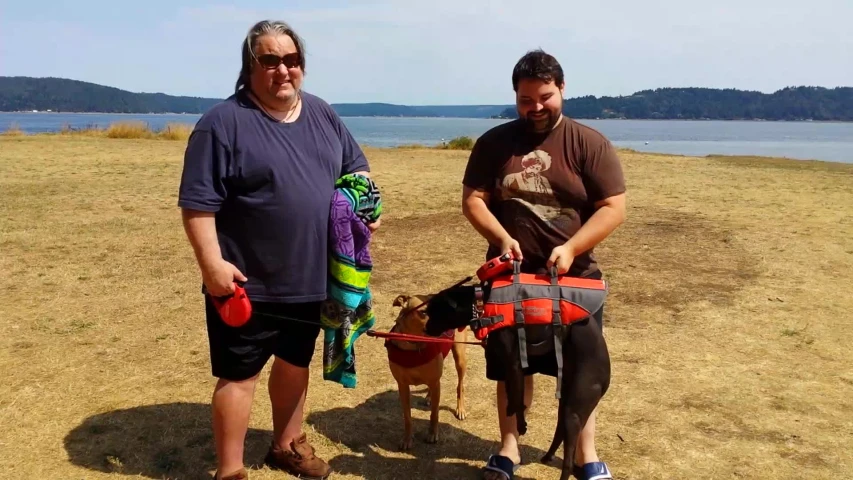 two men standing on grass next to a lake