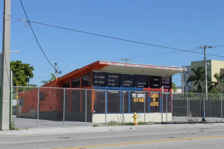 a fenced off building with a sign and a fire hydrant behind it