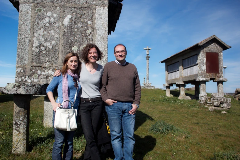 a man and two women standing next to a stone house