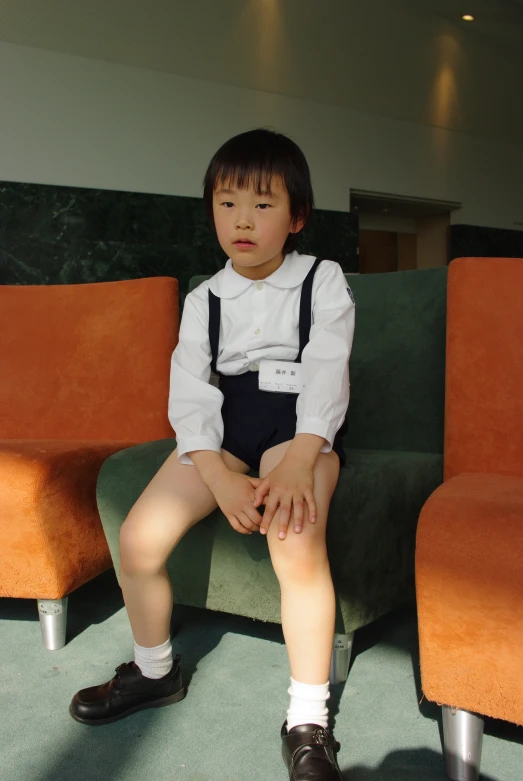 a small boy sitting on an orange couch