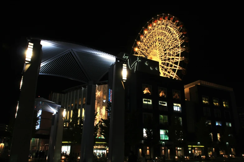 a lighted ferris wheel sitting next to tall buildings