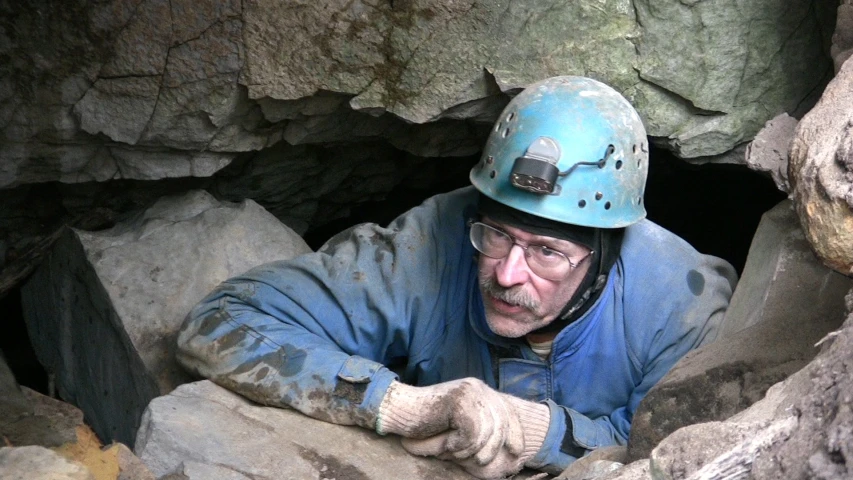 a man in a blue jacket and helmet is in a cave