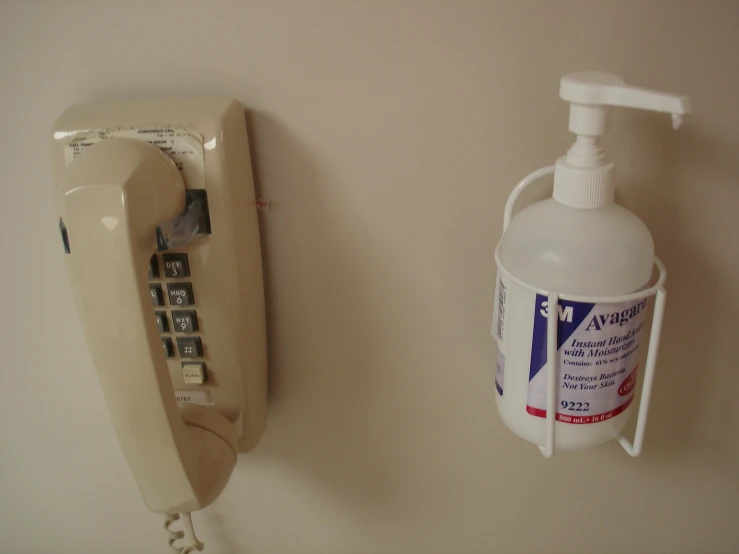 a white phone a cup and a soap dispenser