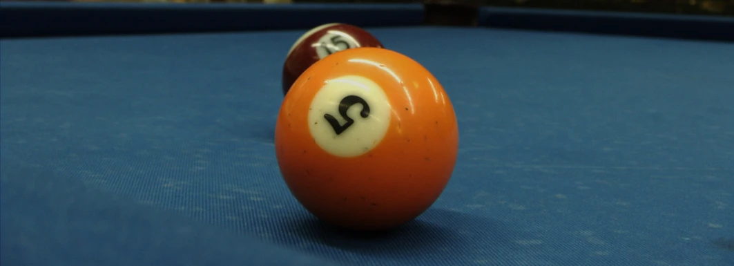 an orange pool ball with white letters in front of it