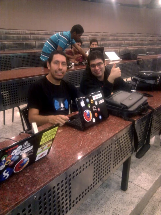 two people sitting behind a counter with laptop computers on it