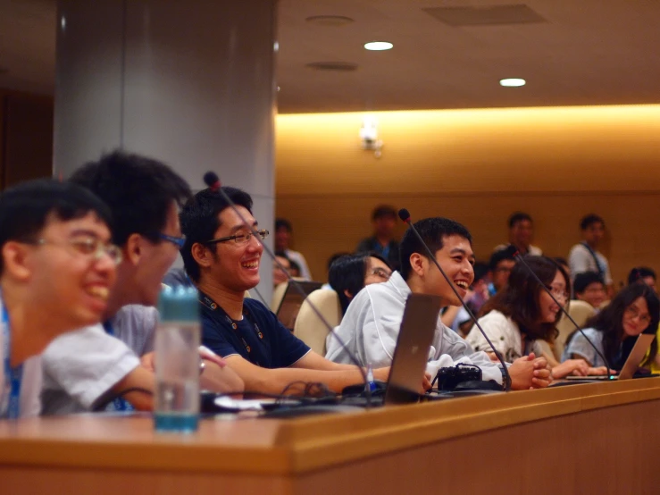 a row of people sitting at a long table smiling