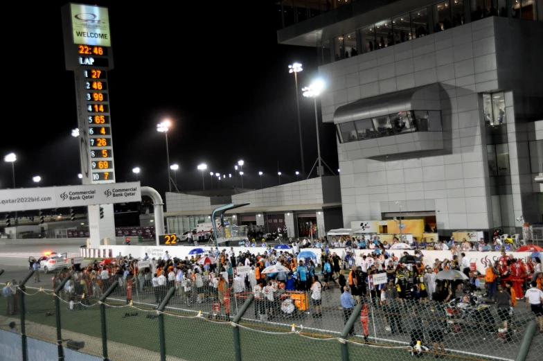 people standing on the side walk outside a large stadium