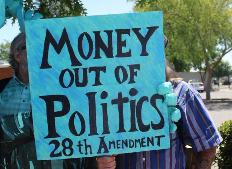 a group of people hold up a sign that says money out of politics