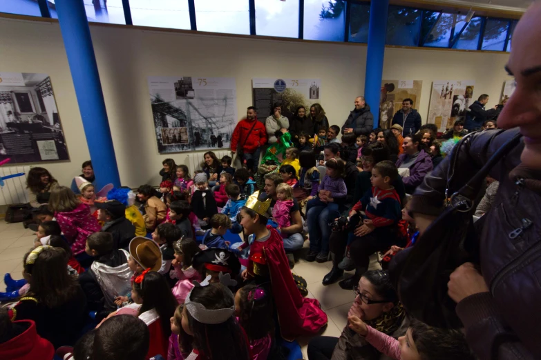 children wearing costumes are gathered in a hall for an event