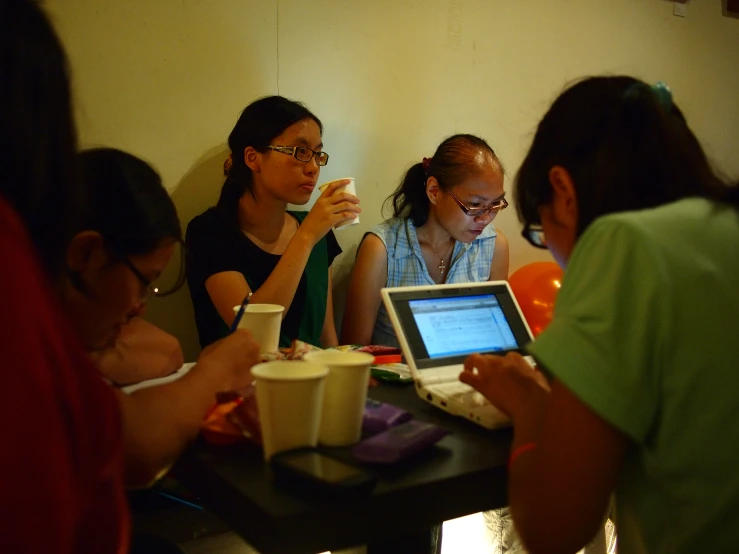 several people sitting at a table with a laptop