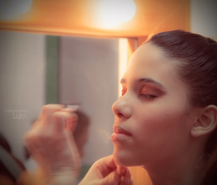 a woman using makeup in front of a mirror
