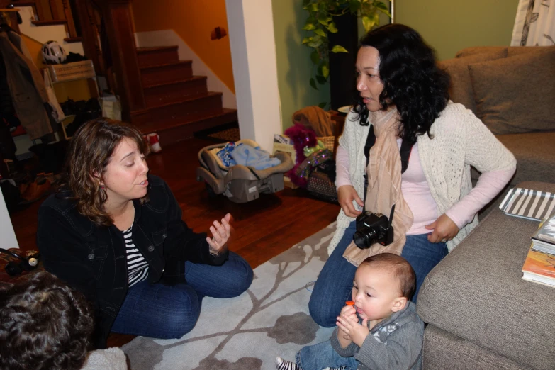 two women in a living room with a toddler sitting down