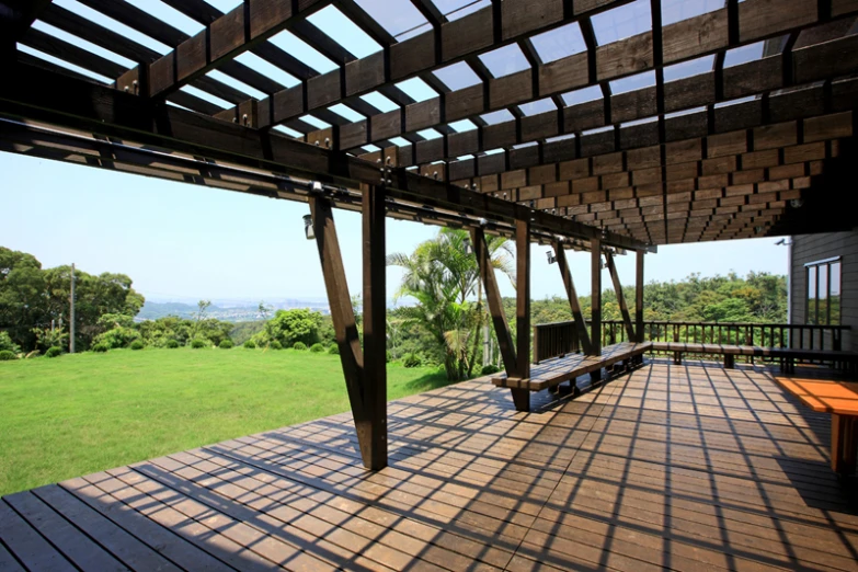 a wooden porch with some benches underneath a pergolated roof