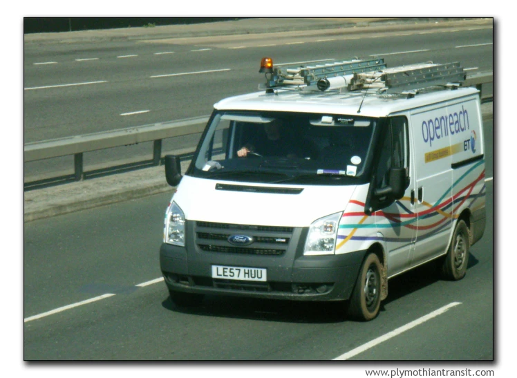 the van is driving down the road on a sunny day