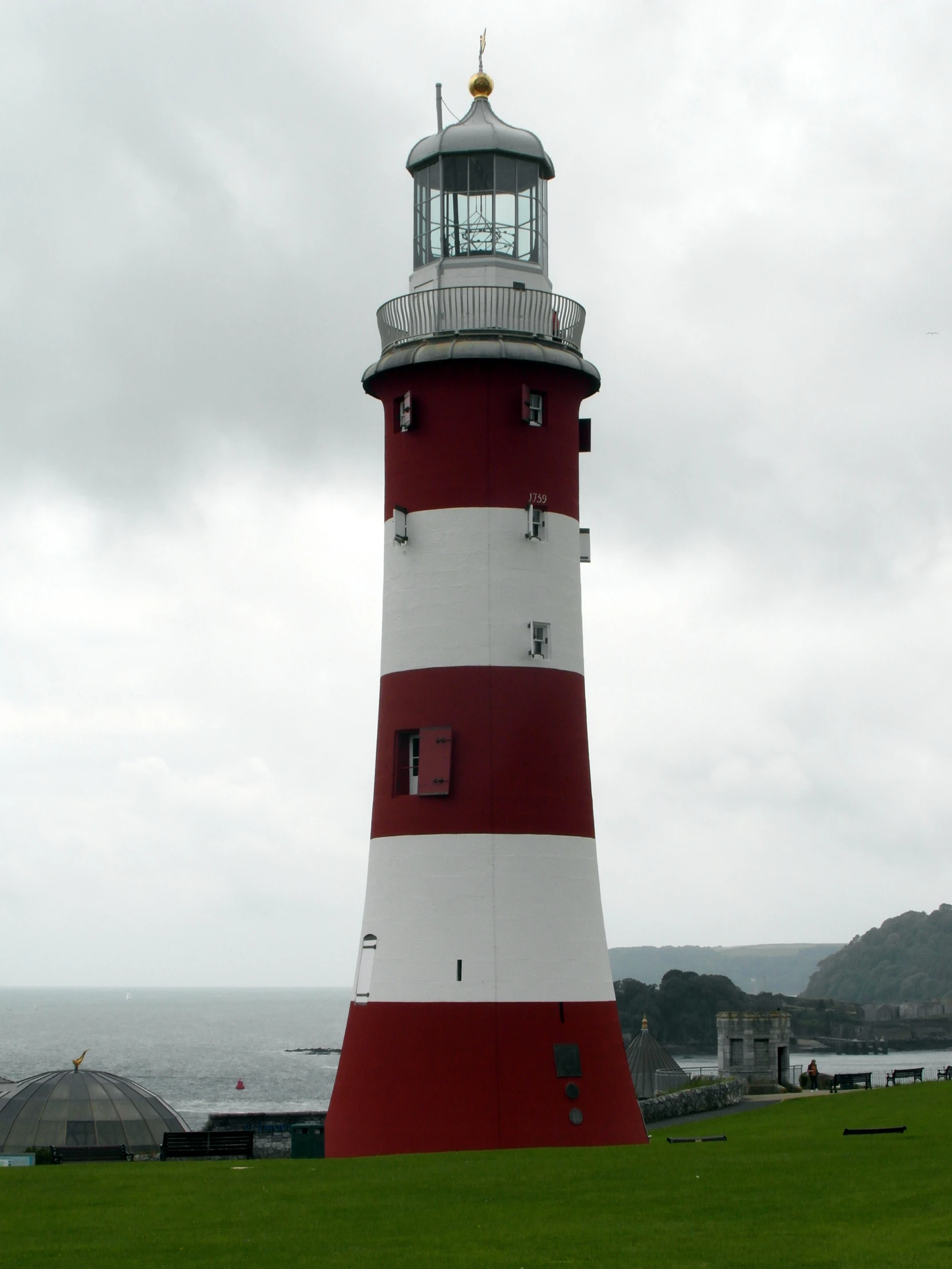 a small red and white lighthouse in the middle of a field