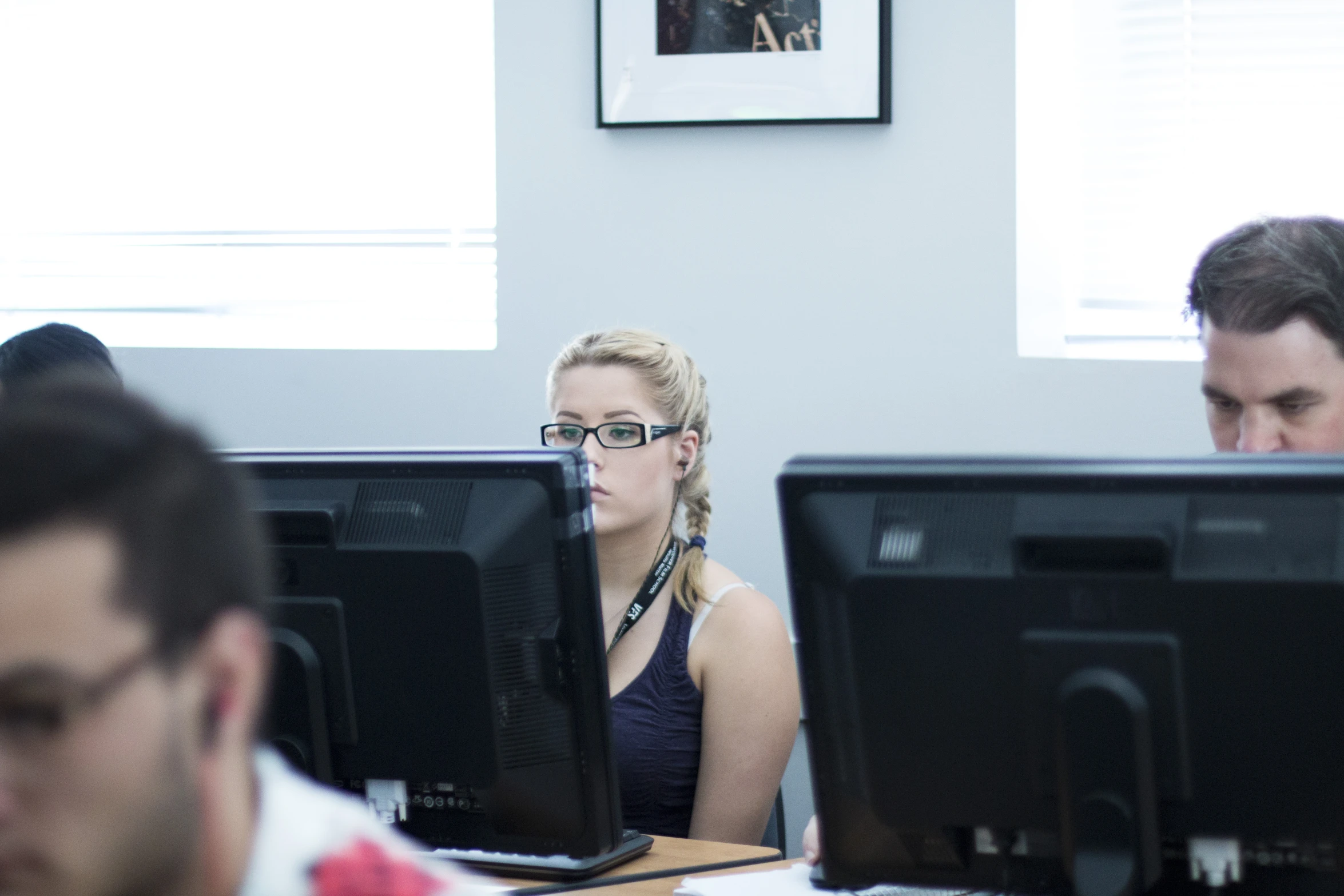 a group of people using computer monitors at desk