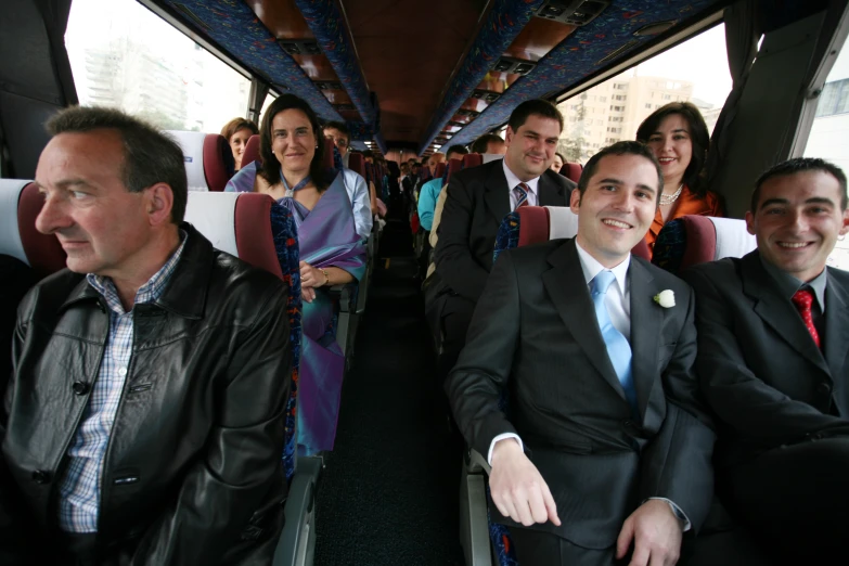 people smiling while sitting in seats on a bus