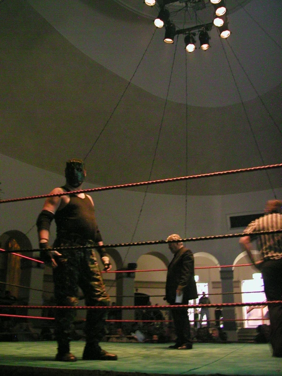 a man in the middle of a ring with a referee standing behind him