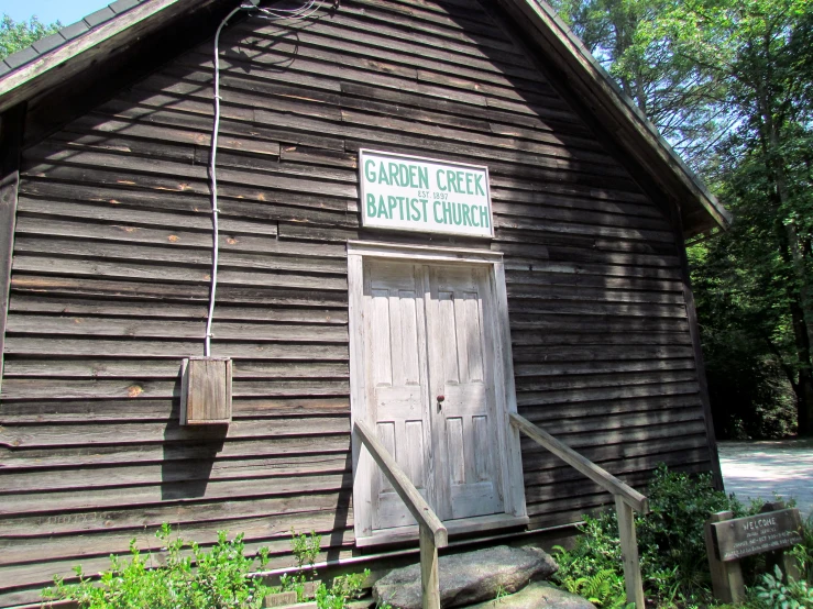 the wooden barn has an open front door and is green and white