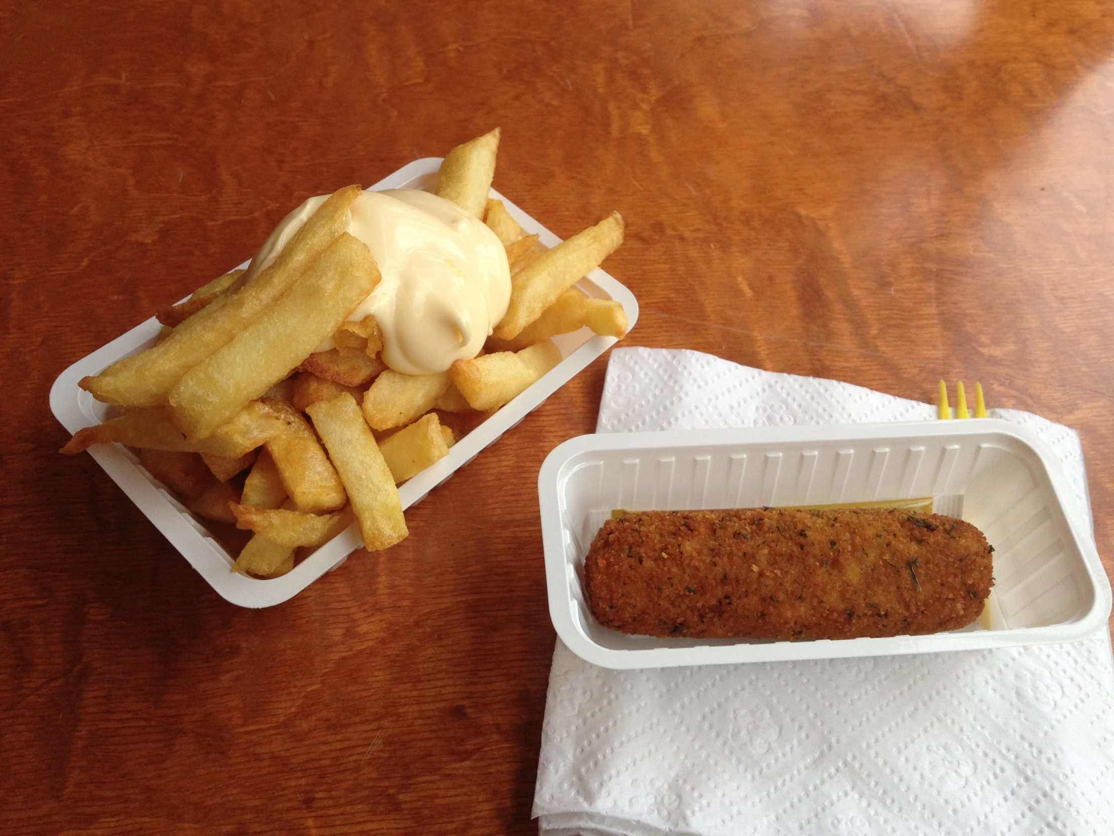 two plastic takeout containers with a sandwich and french fries on a table