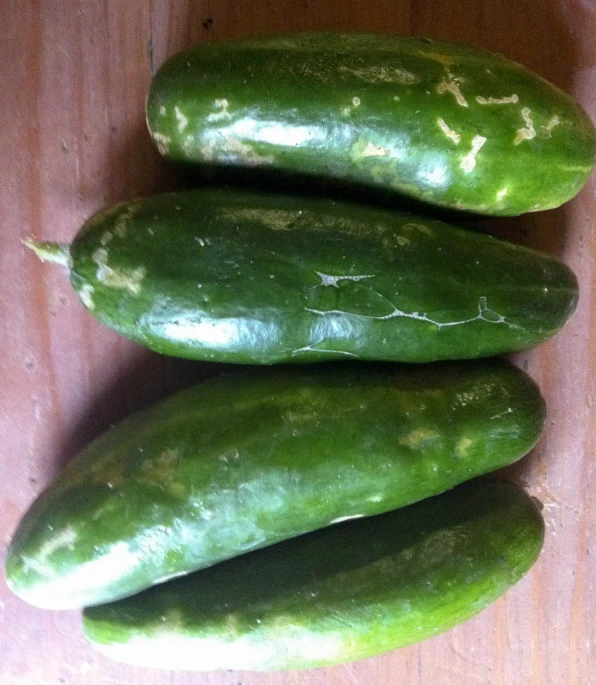 four cucumbers are piled on a table