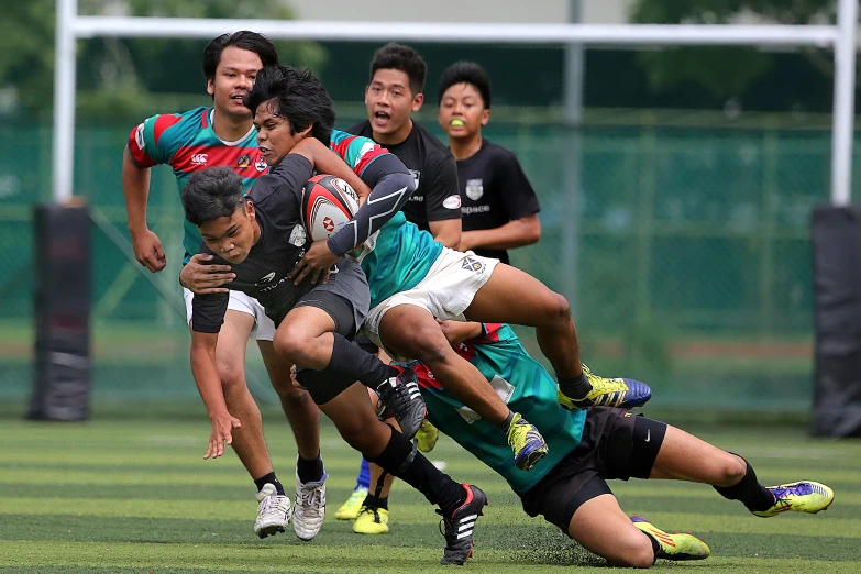 a rugby player is trying to get the ball out of a tackle